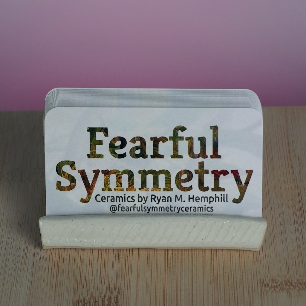 Business cards on a wooden table stating "Fearful Symmetry, Ceramics by Ryan M. Hemphill"